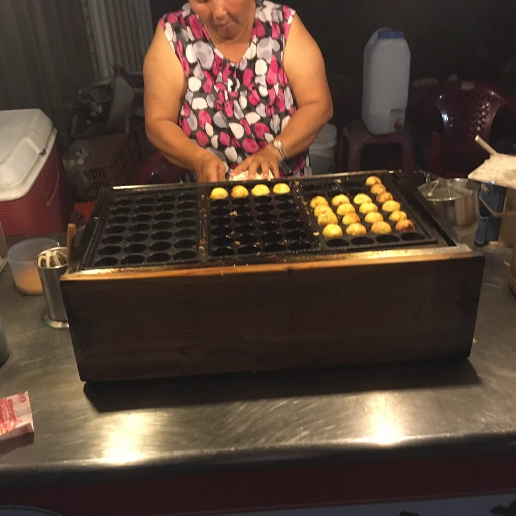 たこ焼きを焼いている女の人の写真